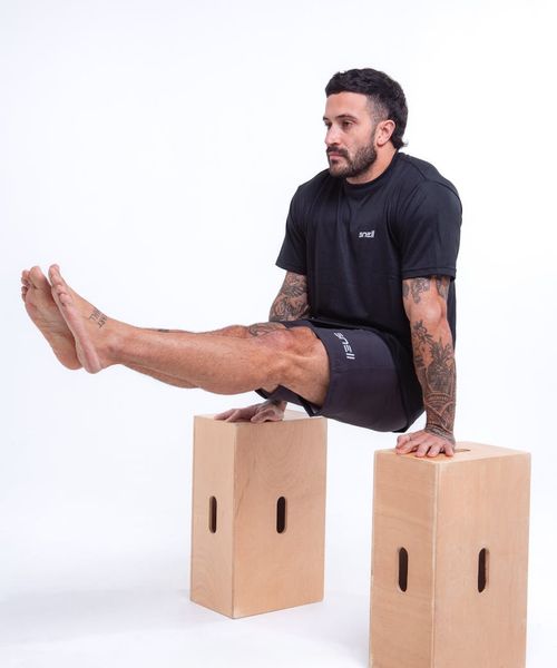 Man performing a controlled strength exercise in a modern, dark gym.